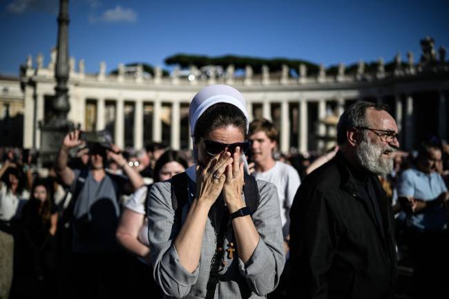 A nun reacts as white smoke (unseen) signals that cardinals elected a new pope during their conclave in the Vatican on May 8, 2025. Thick black smoke billowed on May 8, 2025, from the chimney of the Sistine Chapel in a sign that cardinals again failed to elect a new head of the Catholic Church. (Photo by JEFF PACHOUD / AFP)