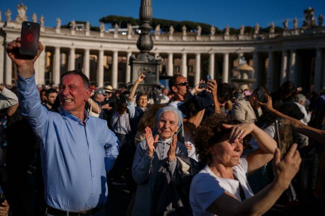 A nun (C) reacts as white smoke (unseen) signals that cardinals elected a new pope during their conclave in the Vatican on May 8, 2025. Thick black smoke billowed on May 8, 2025, from the chimney of the Sistine Chapel in a sign that cardinals again failed to elect a new head of the Catholic Church. (Photo by Dimitar DILKOFF / AFP)