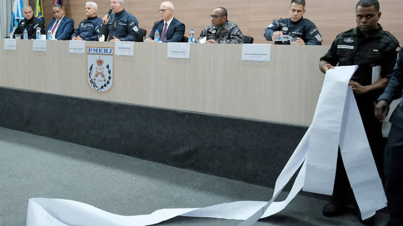 Policial segura ficha criminal de Thiago da Silva Folly durante coletiva de imprensa