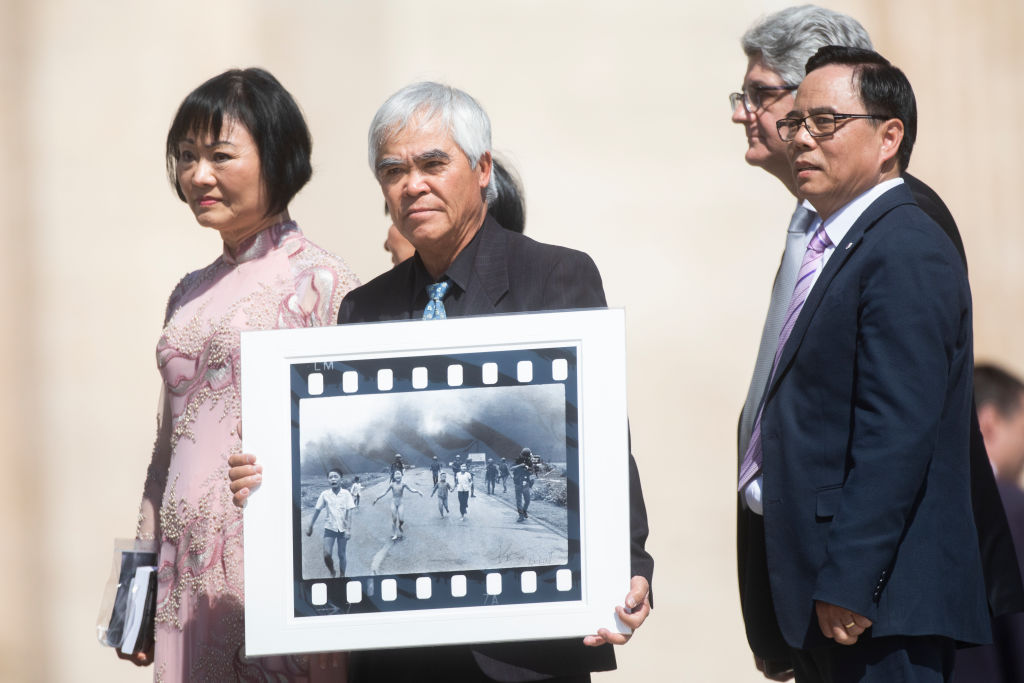VATICAN CITY, VATICAN - MAY 11: Nick Ut (C) holds his Pulitzer and World Press Photo Award, 1972 photograph Napalm Girl, depicting Kim Phuc (L) as they attend Pope Francis general weekly audience in St. Peter's Square, on May 11, 2022 in Vatican City, Vatican. (Photo by Alessandra Benedetti - Corbis/Corbis via Getty Images)