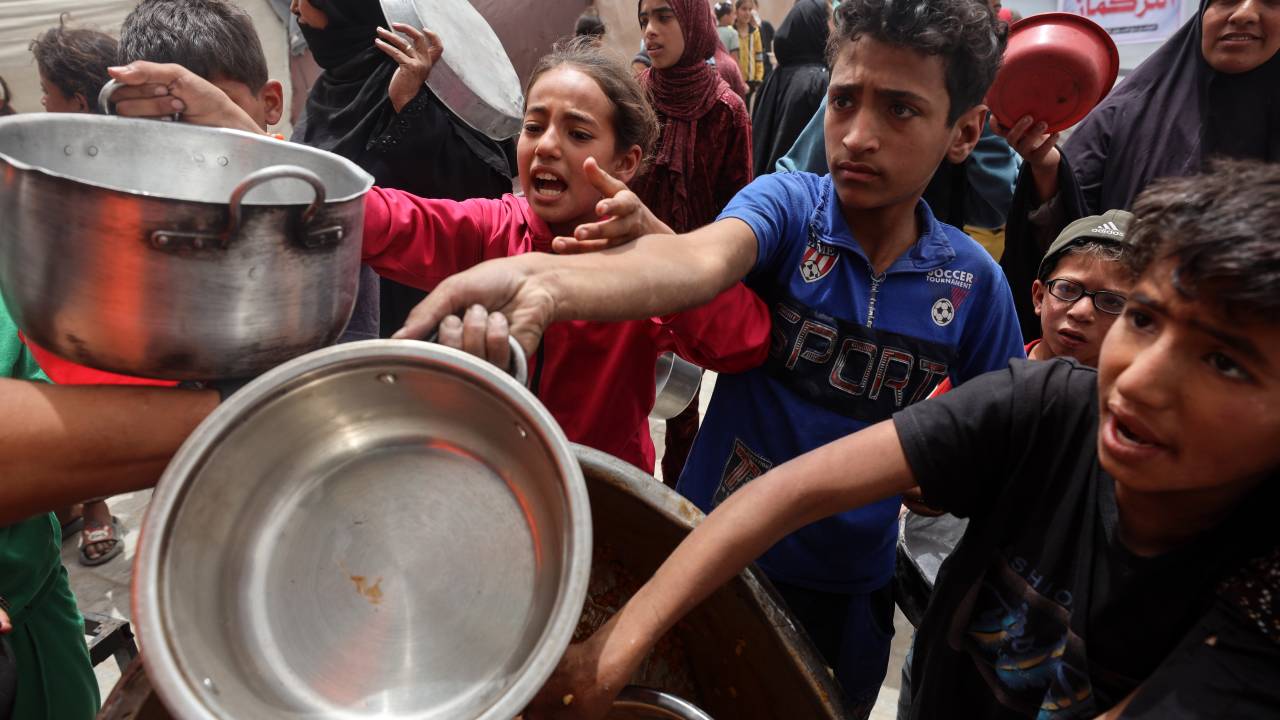 Palestinos deslocados fazem fila para receber uma porção de comida na Cidade de Gaza. 30/04/2025