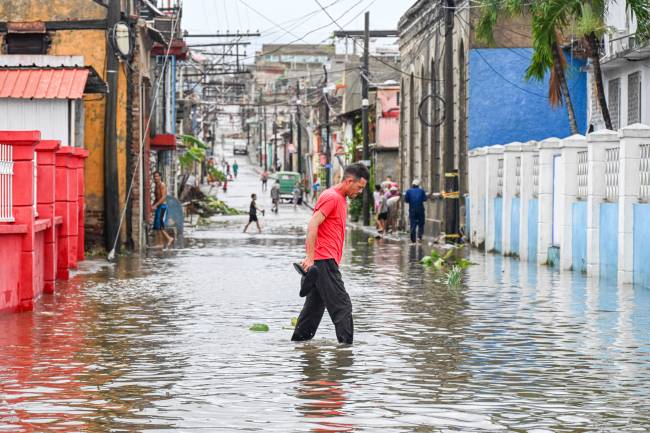 A man walks through a flooded street in a neighborhood affected by Hurricane Melissa in Santiago de Cuba on October 29, 2025. A powerful Hurricane Melissa made landfall in eastern Cuba on Wednesday, causing damage and flooding to homes and streets in Santiago de Cuba province, an AFP team on the ground reported. (Photo by YAMIL LAGE / AFP)