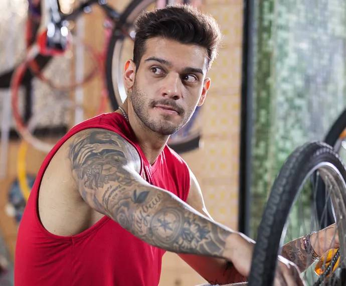 Foto do cantor Lucas Lucco usando uma camiseta regata vermelha e braço tatuado