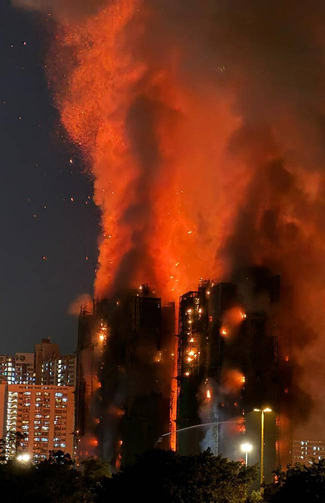Thick smoke and flames rise as a major fire engulfs several apartment blocks at the Wang Fuk Court residential estate in Hong Kong's Tai Po district on November 26, 2025. At least four people were killed when a fire engulfed several high-rise blocks in a Hong Kong residential estate on November 26, the government said, with media reporting that some residents were trapped inside. (Photo by Yan ZHAO / AFP)