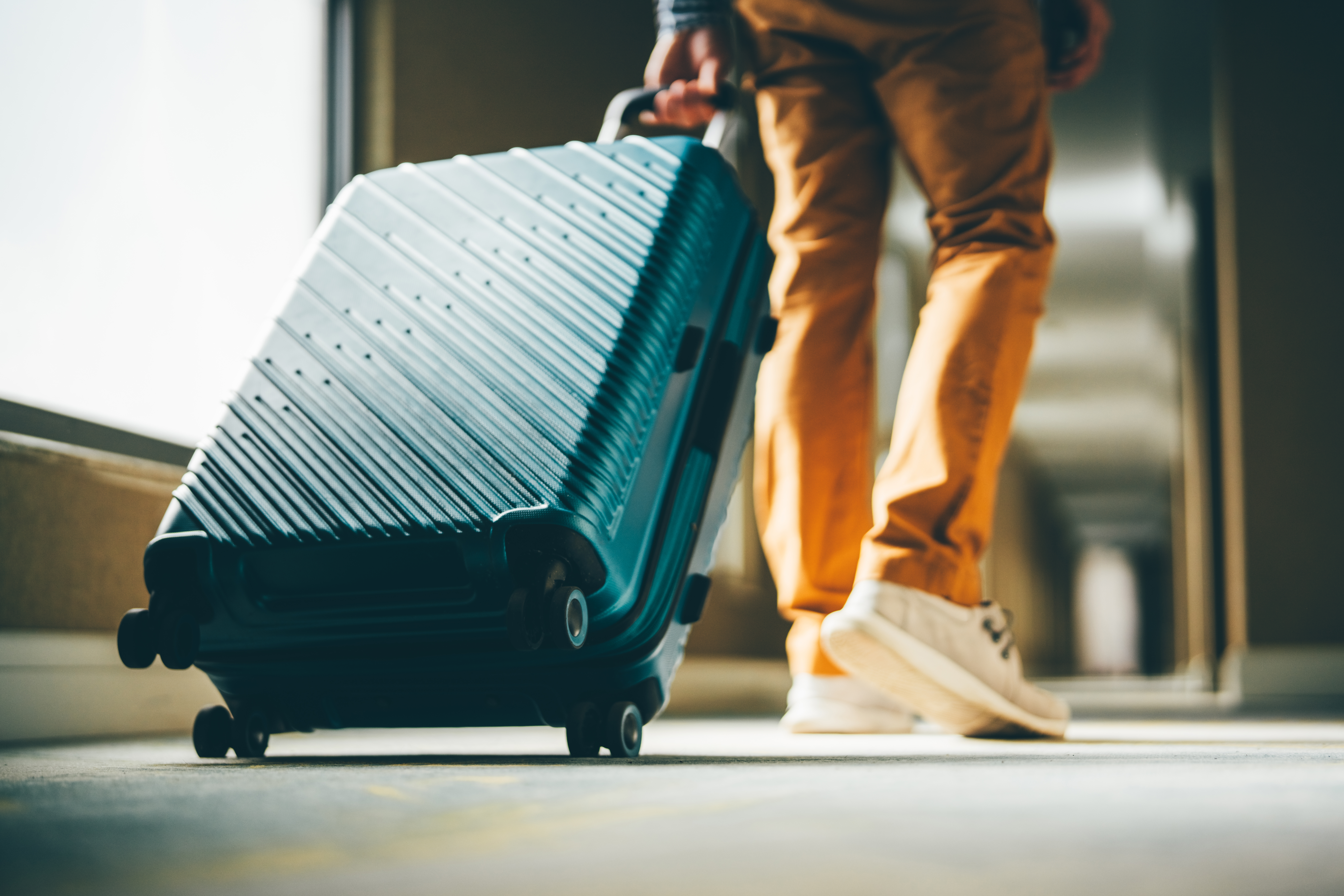 A man walks down the hotel corridor with luggage.