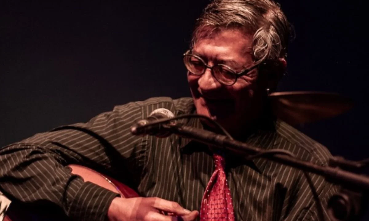 Foto do cantor Julio Reny tocando violão