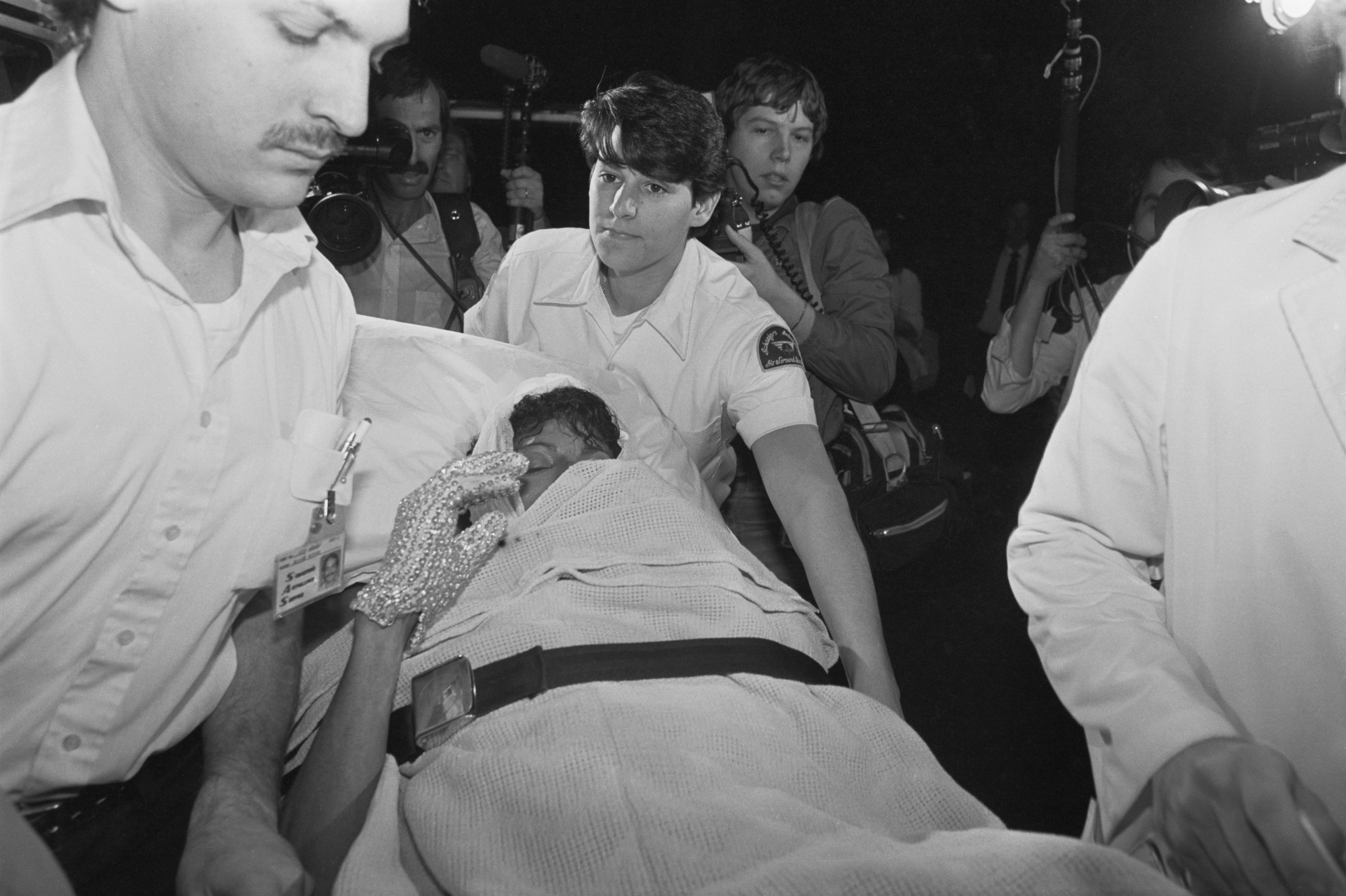 Michael Jackson sendo levado ao hospital ap&oacute;s acidente em comercial da Pepsi, 1984