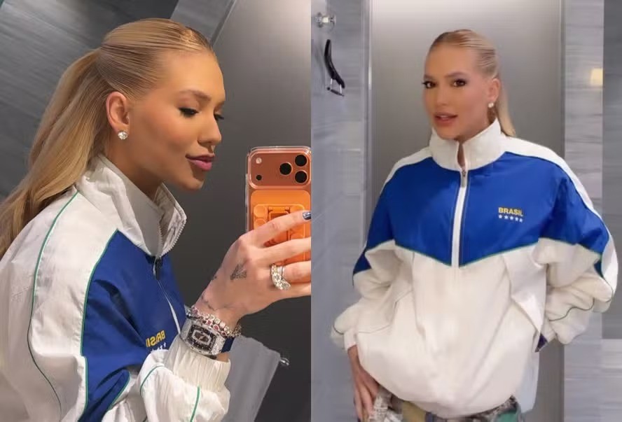 Mulher loira de rabo de cavalo, usando jaqueta azul e branca com BRASIL e cinco estrelas douradas, posa em duas fotos. Na esquerda, ela tira uma selfie no espelho com um celular laranja, exibindo anéis e pulseiras. Na direita, ela está de frente para o espelho, sorrindo levemente