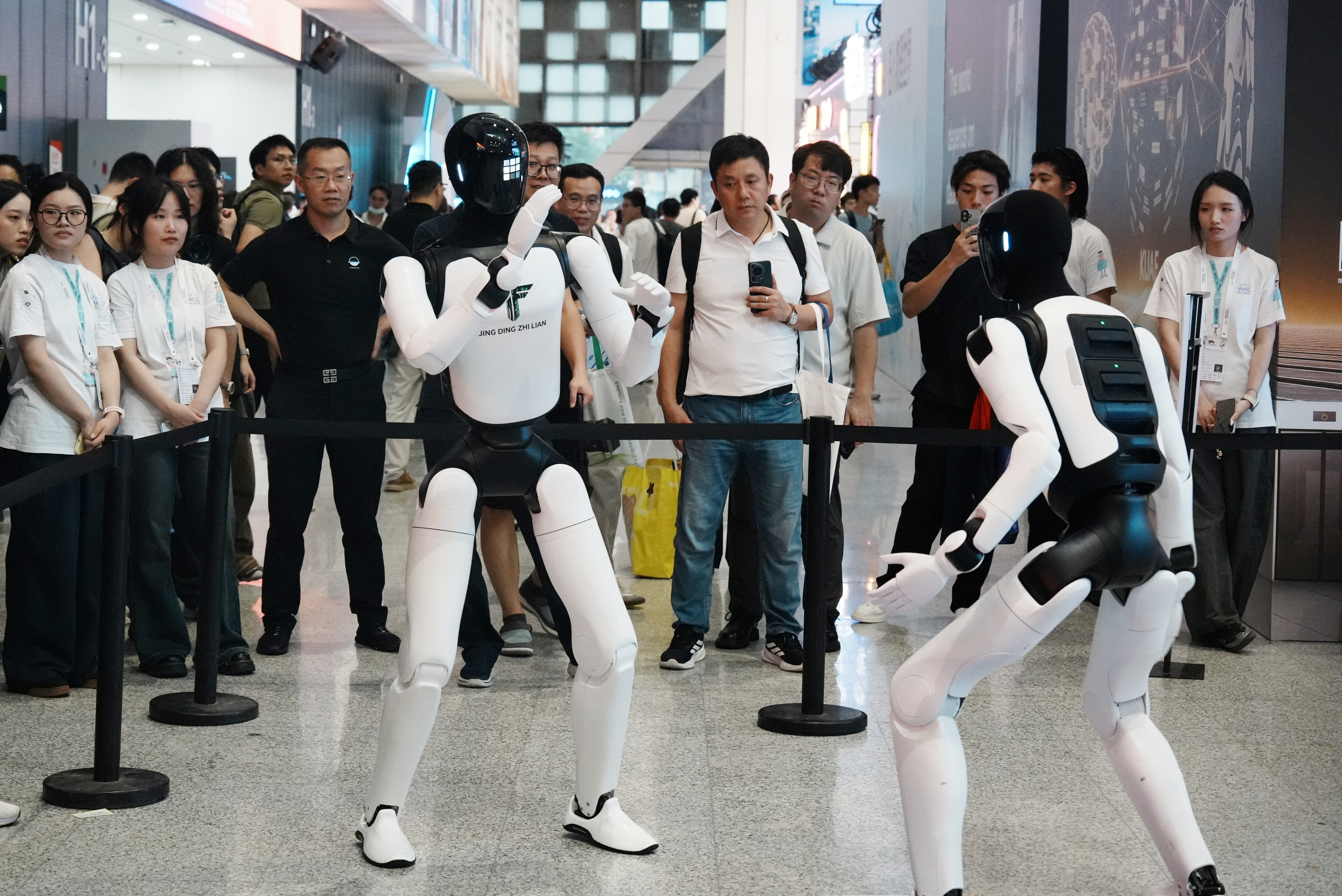 Espectadores observam robôs humanoides demonstrarem suas habilidades na Conferência Mundial de Inteligência Artificial de 2026, em Xangai, China, em 20 de julho de 2026.